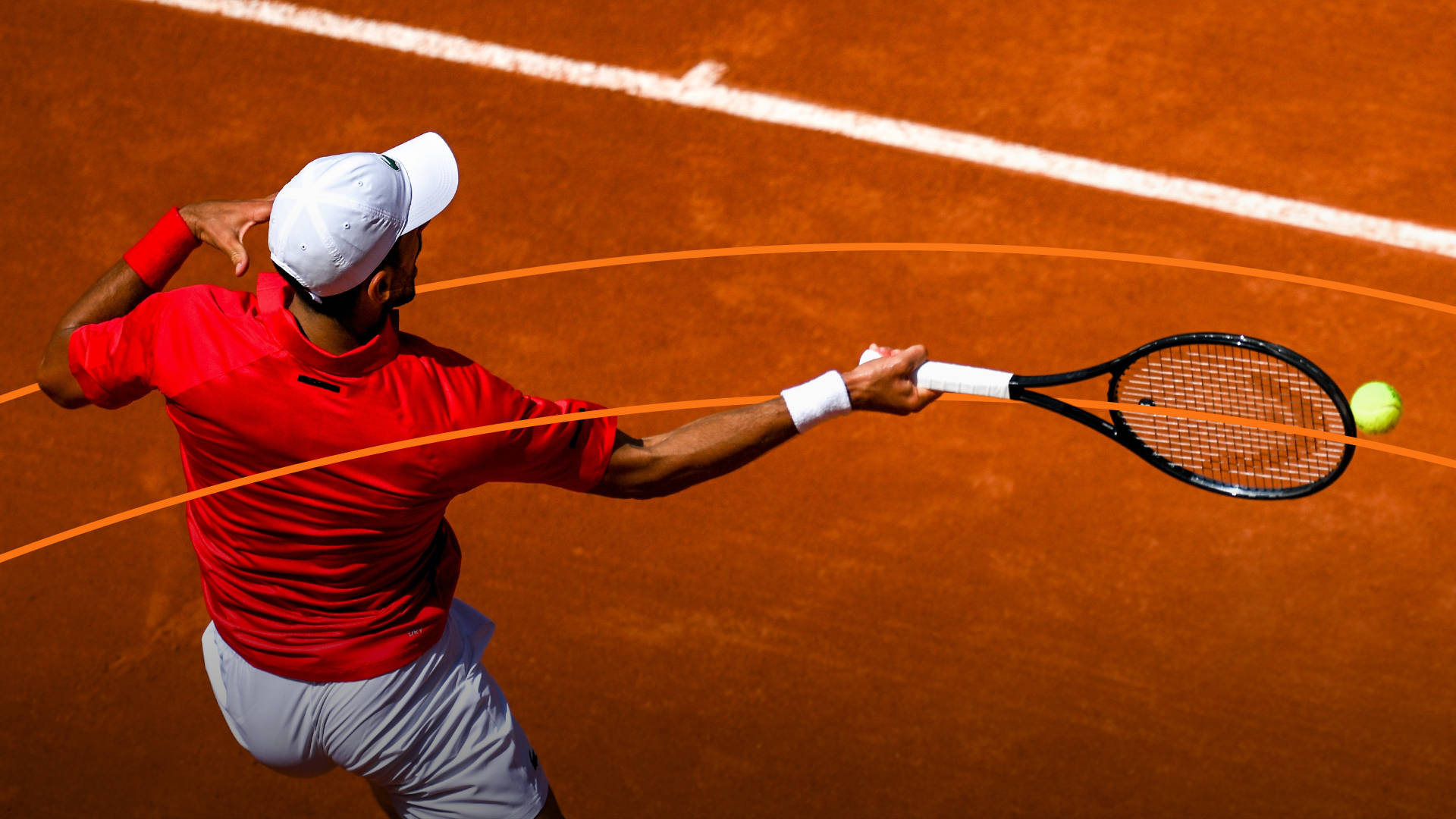 Tenista golpeando una pelota con una raqueta en una cancha de tenis de tierra batida.