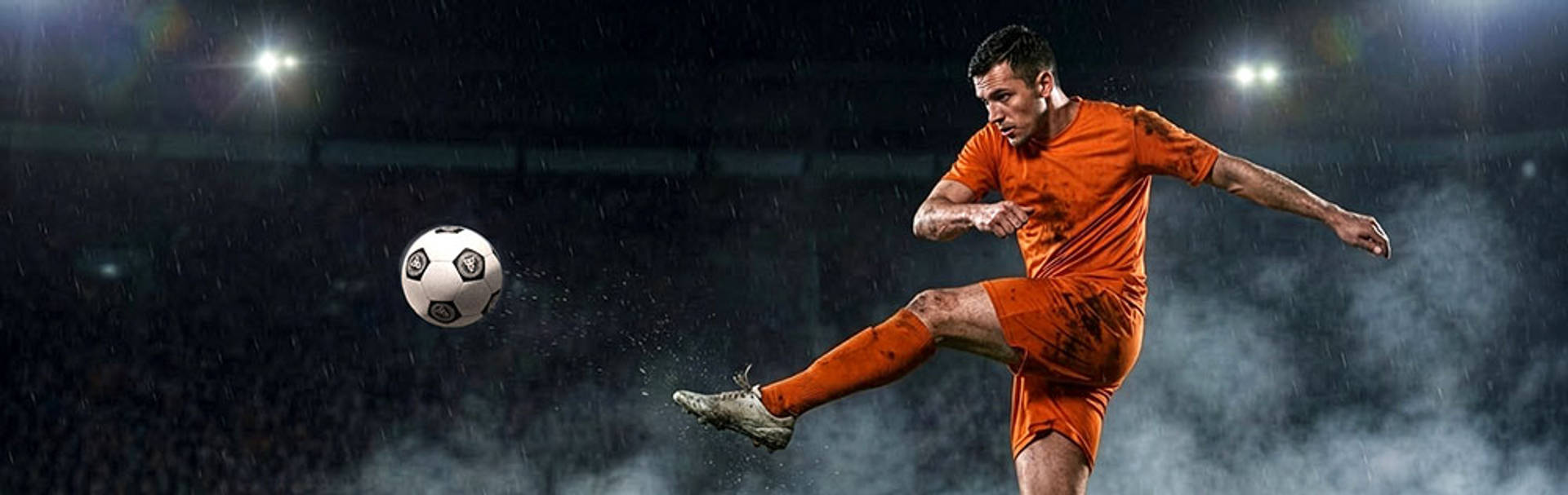 Fußballspieler in Aktion auf dem Spielfeld bei Regen.