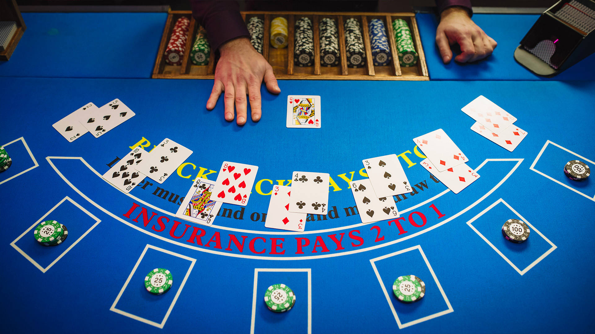 blue blackjack table with pairs of cards scattered across the table