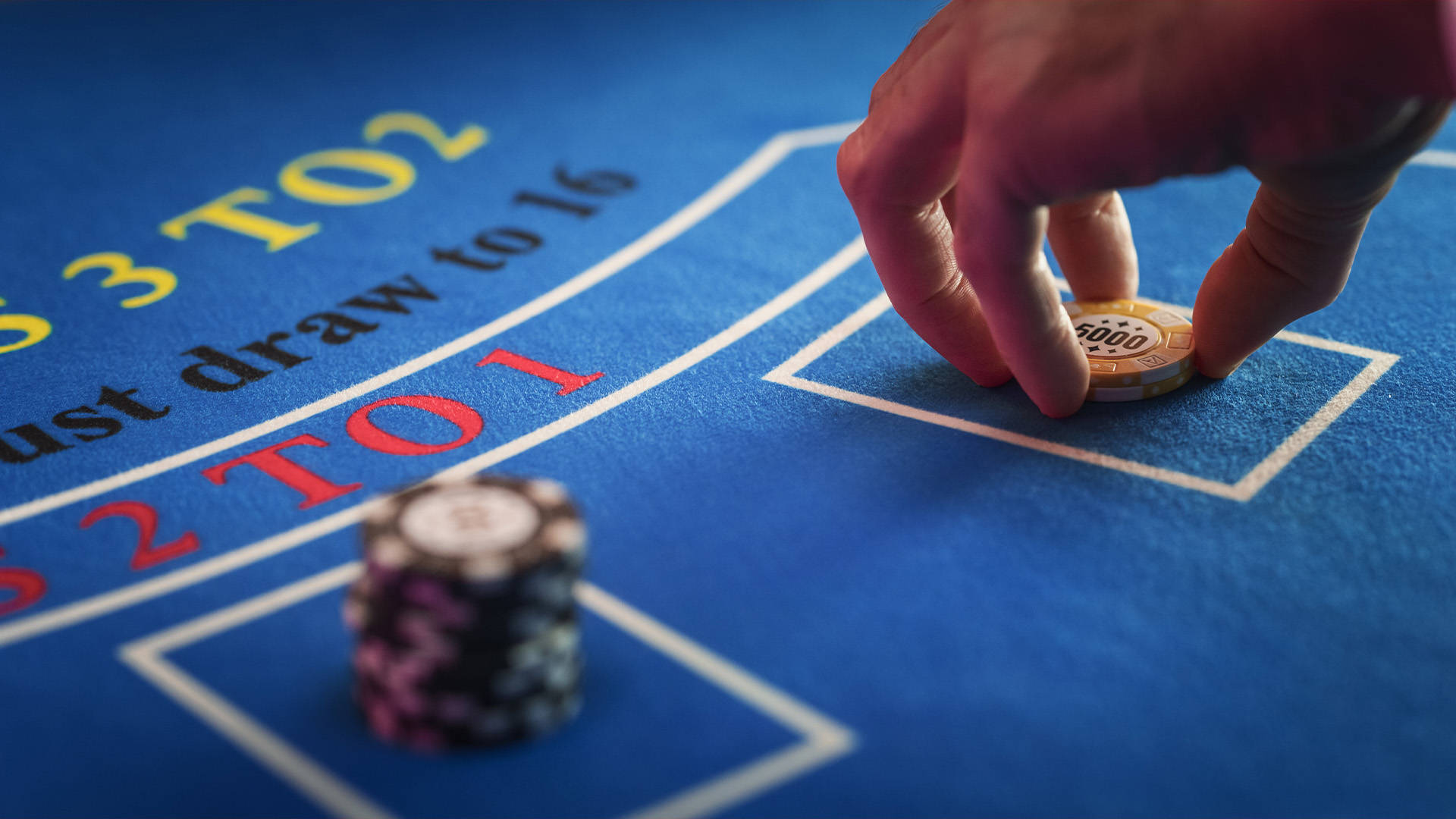 casino chips being placed over the banker section on a baccarat table