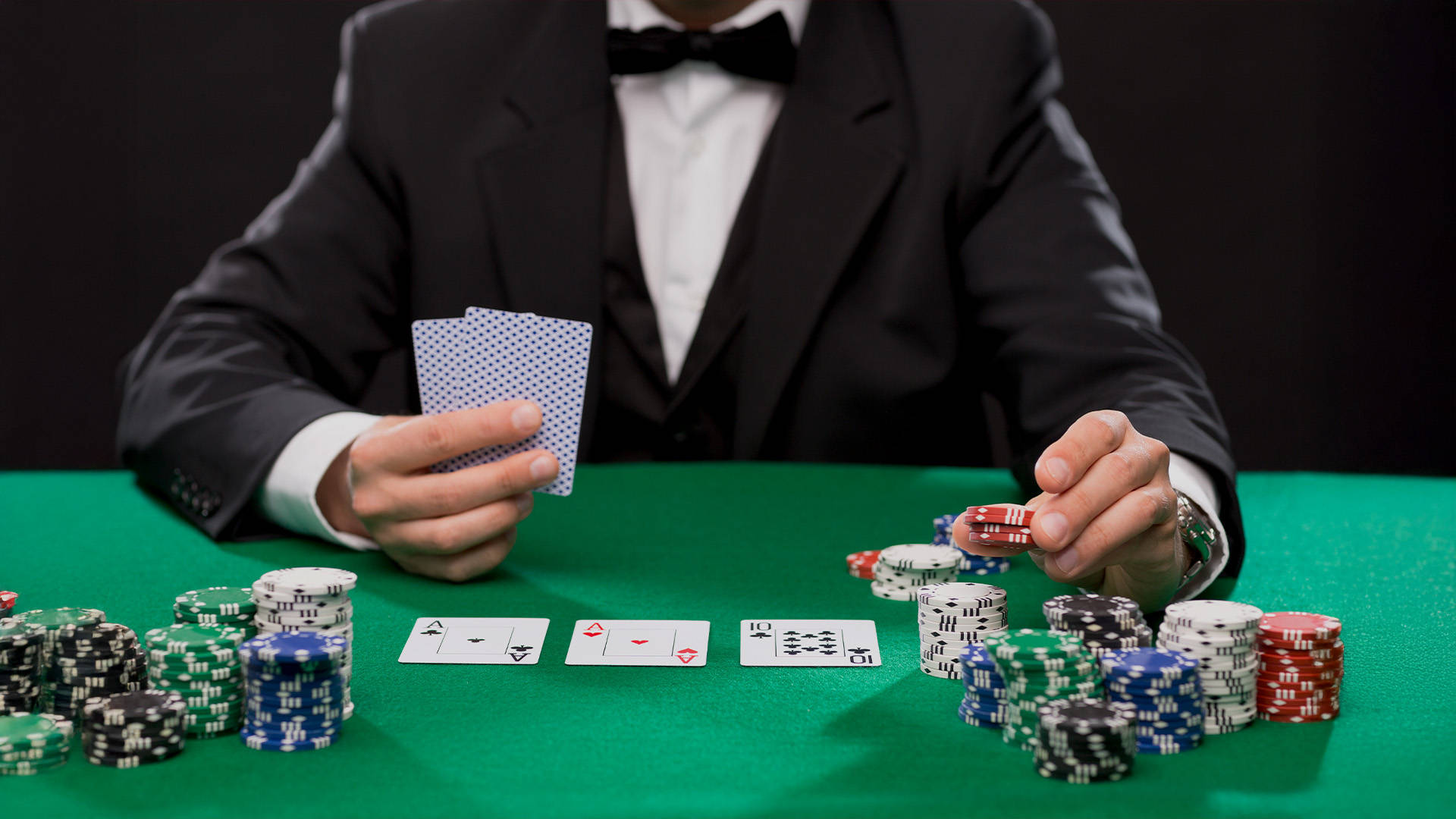 dealer holding a pair of cards with one hand and casino chips in the other