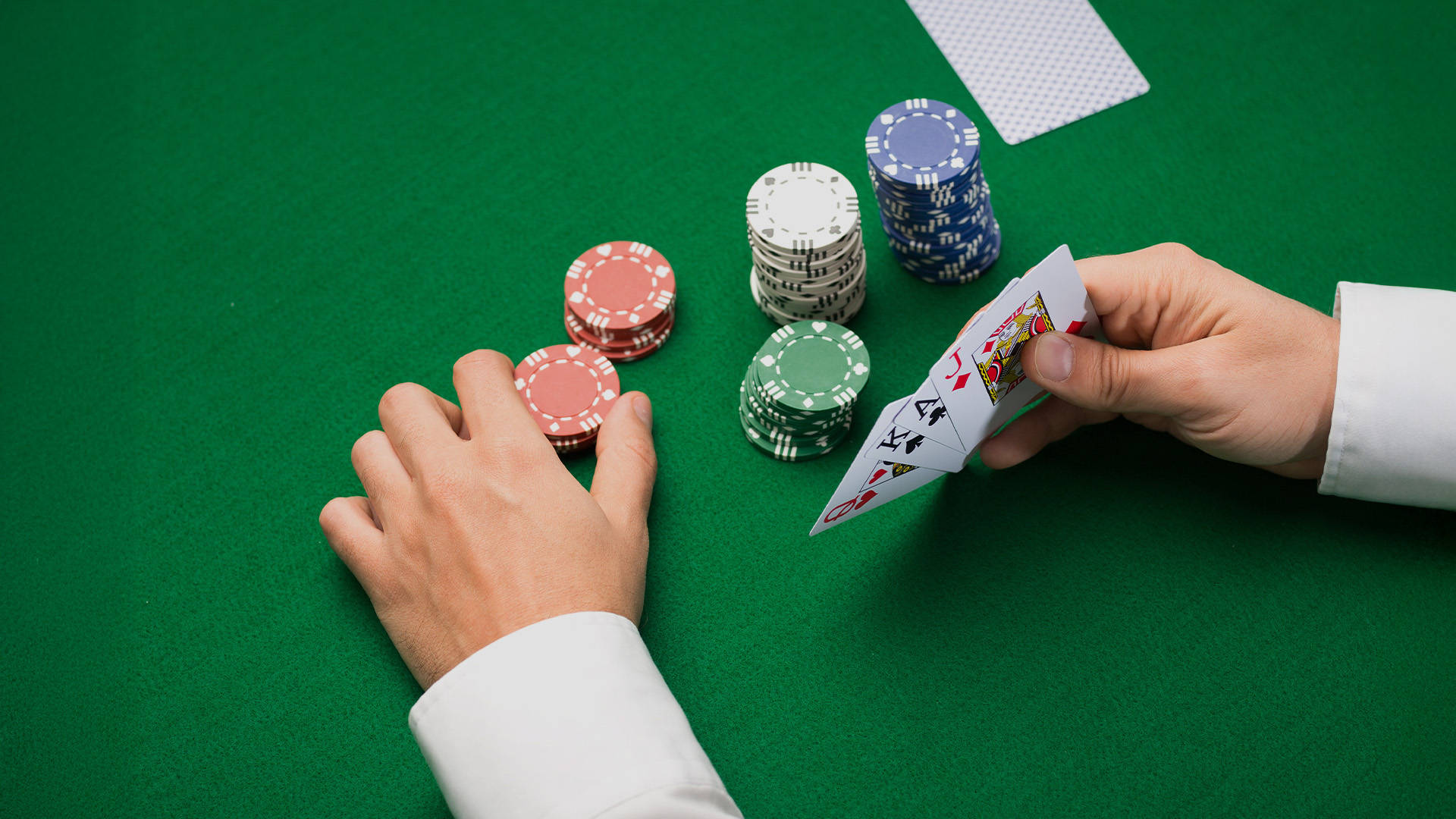dealer holding a hand of cards with casino chips placed in front