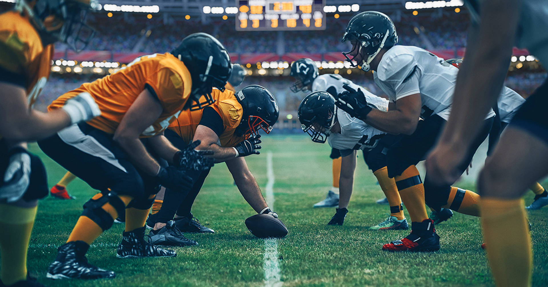 football players at the line of scrimmage facing off ready to snap the ball