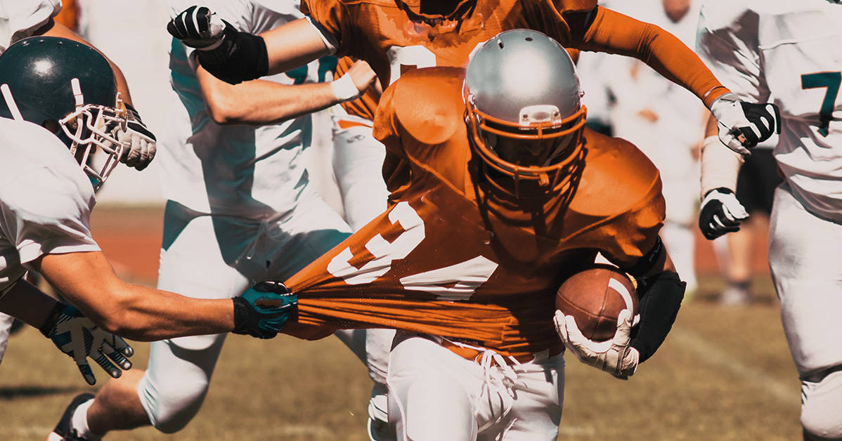 football player running through defences with shirt being pulled back
