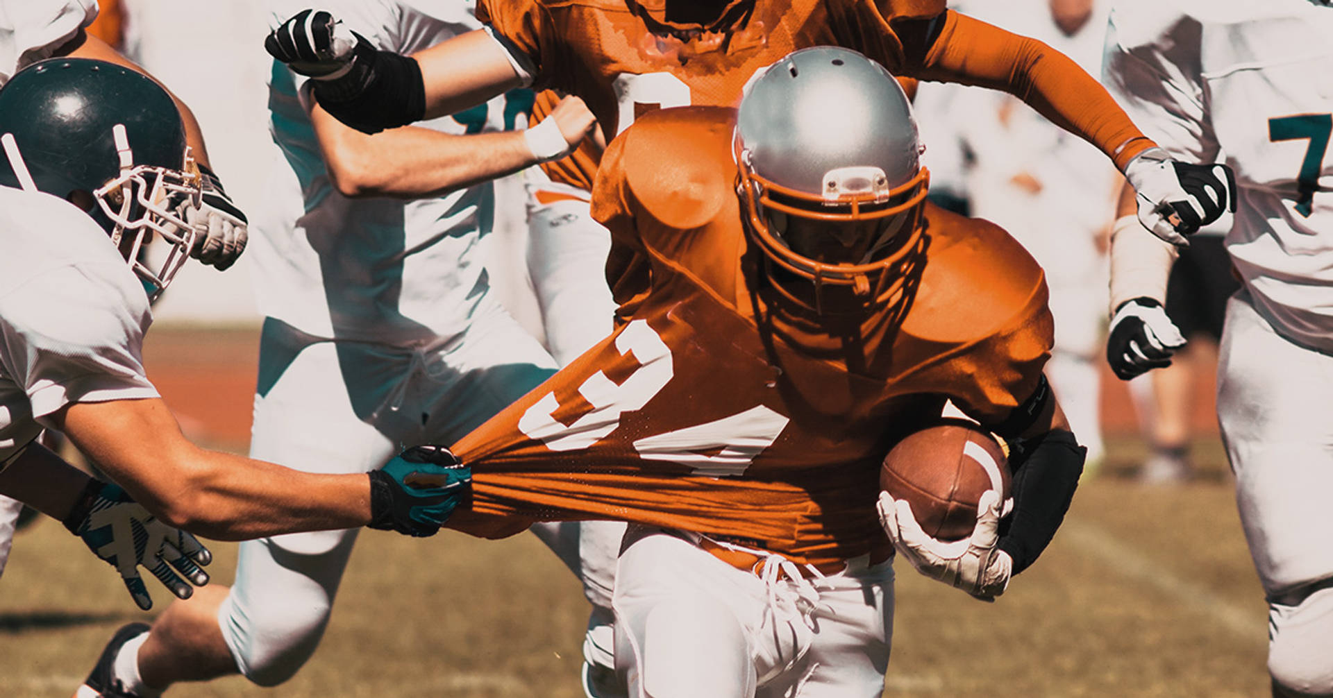 football player rushing through defences with shirt being pulled back
