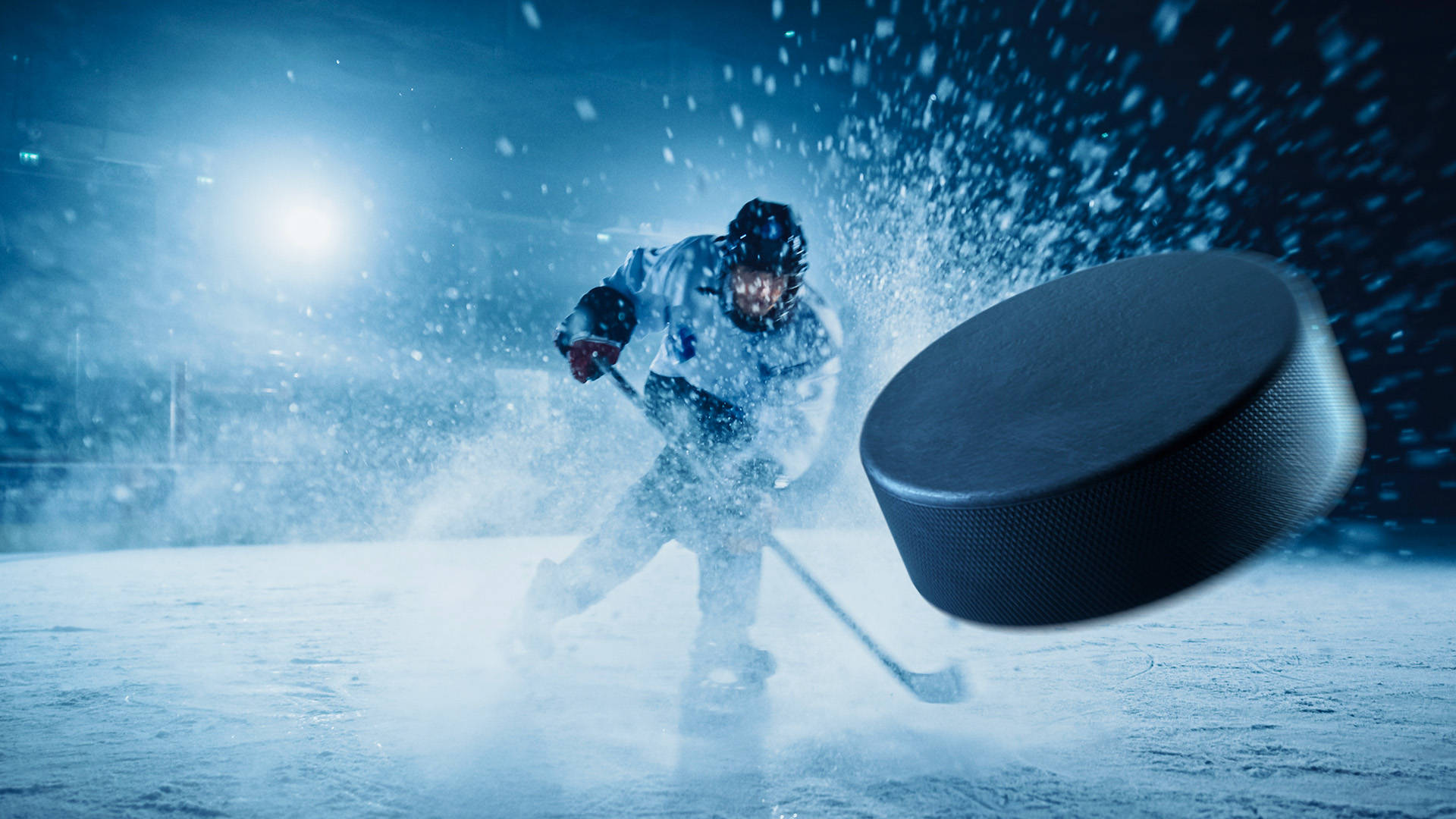 hockey player striking the puck with ice splashing up