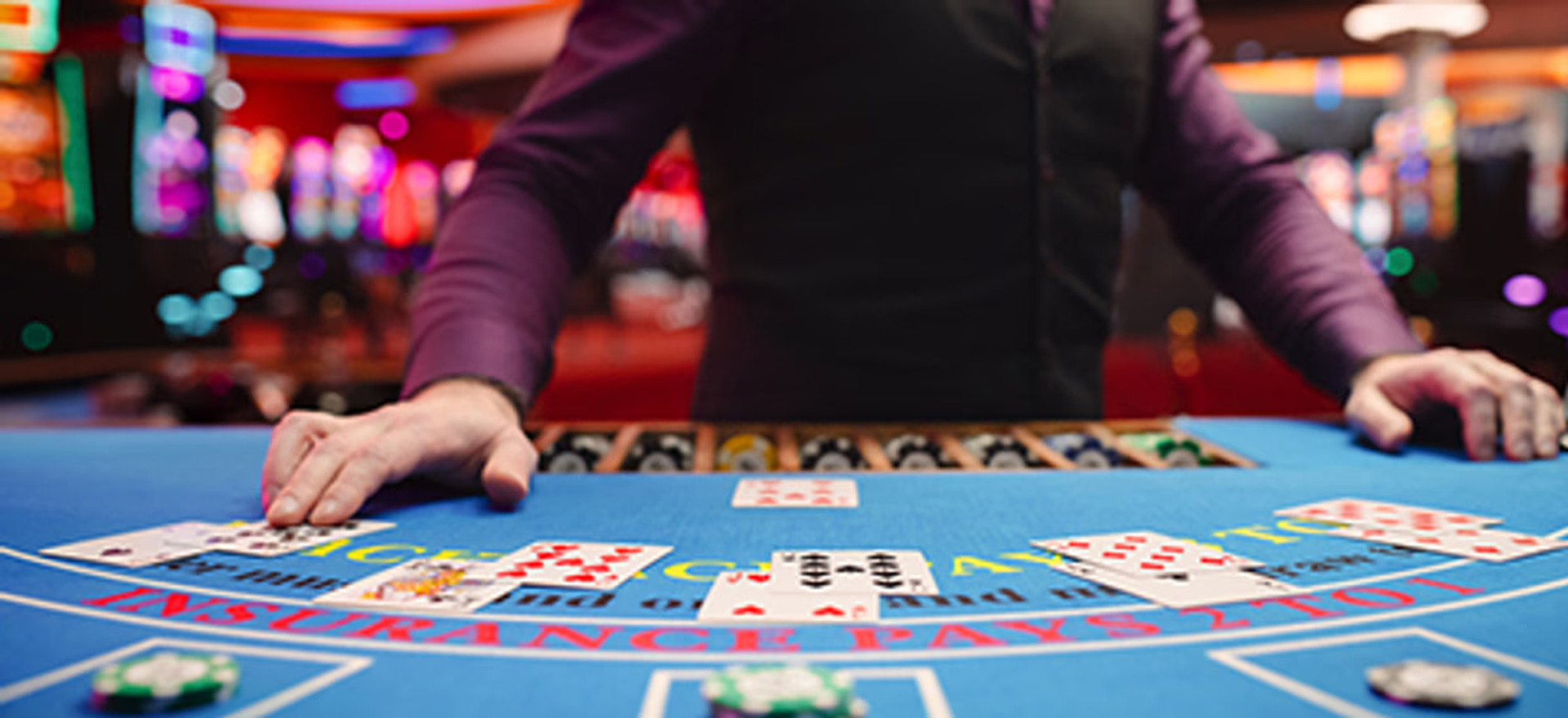 Blackjack-bord med kort og chips, hvor dealeren står klar.