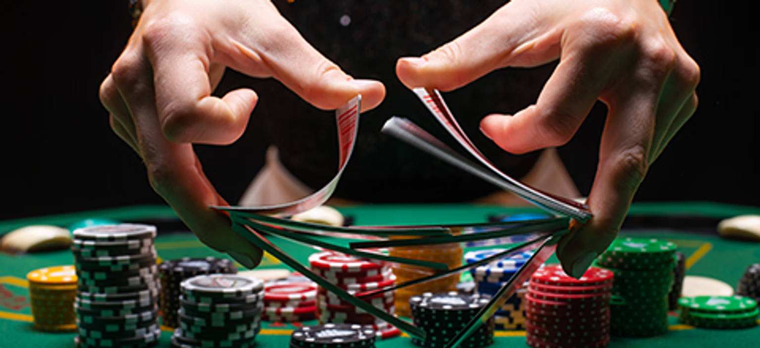 Kort blandes over casinobord med pokerchips i baggrunden