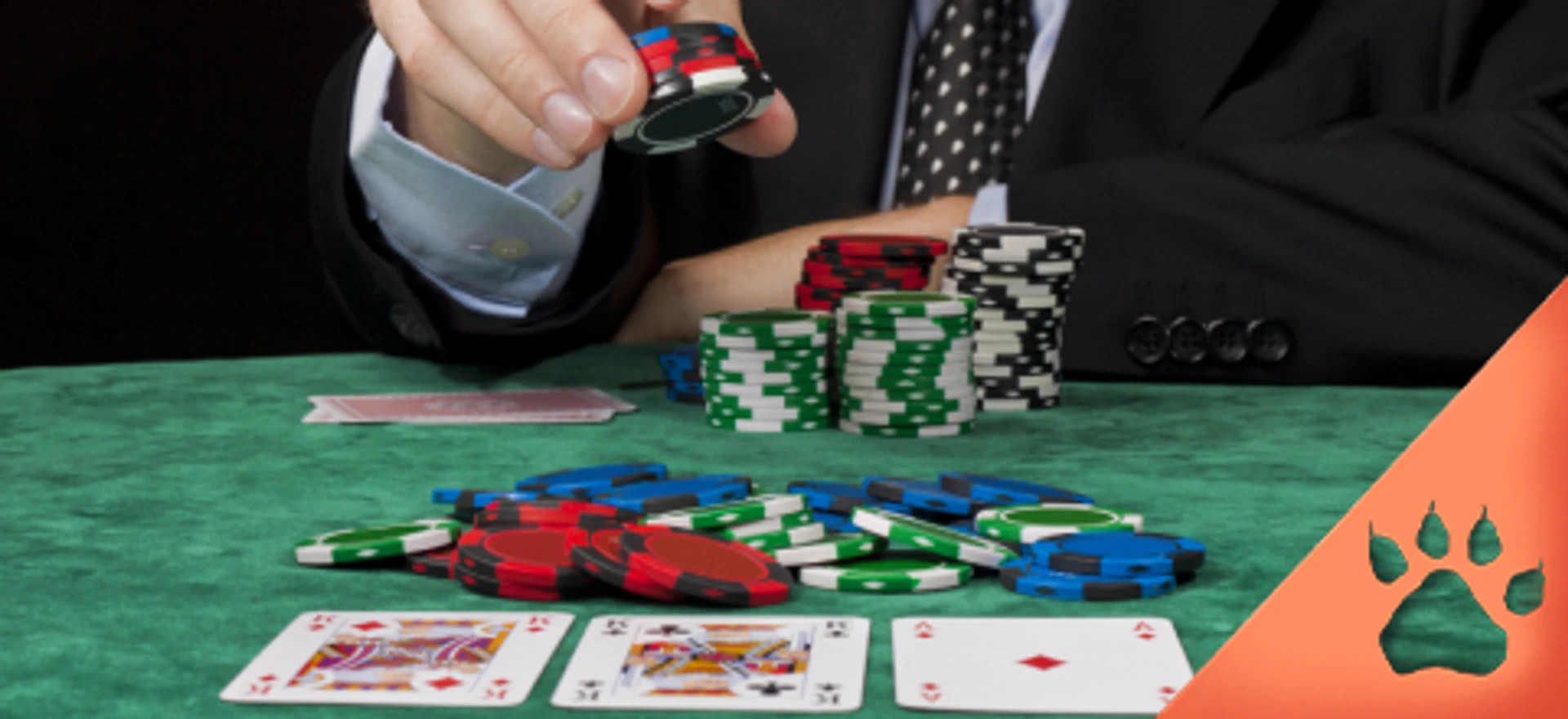 Pokerhånd med kort og jetoner på grønt bord, mens en spiller i jakkesæt placerer indsats