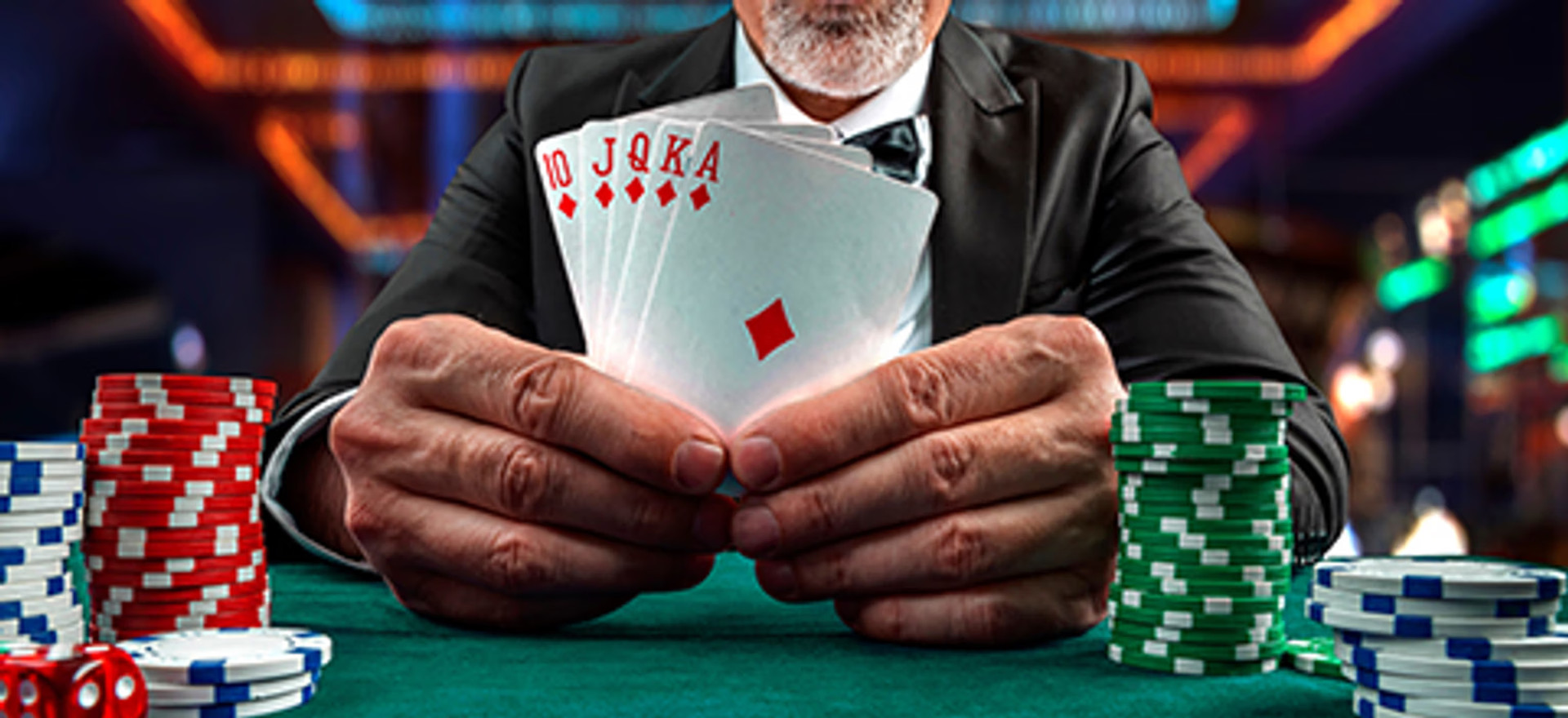 Mand med pokerhænder, chips og kort på et kasinobord.