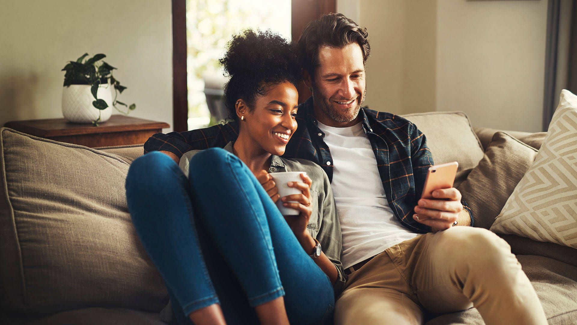 Mand og kvinde tjekker telefon i deres sofa