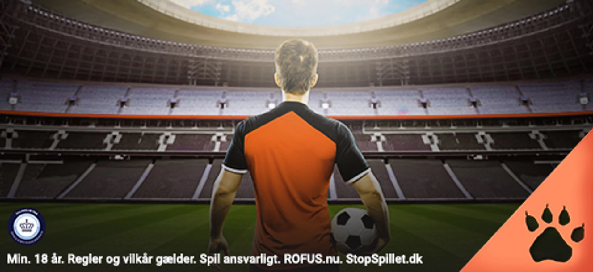 Fodboldspiller i orange trøje med ryggen til står med bolden foran tomt stadion – klar til kamp eller odds