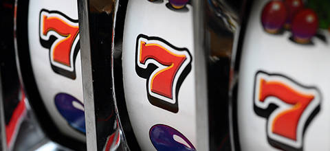 Slot machine reels showing the number 7 and fruit symbols.