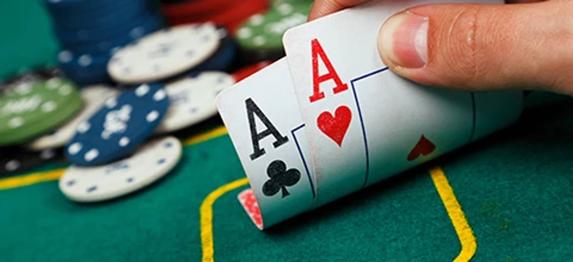 Lähikuva pokerikädestä, jossa on kaksi ässää pokeripöydällä.