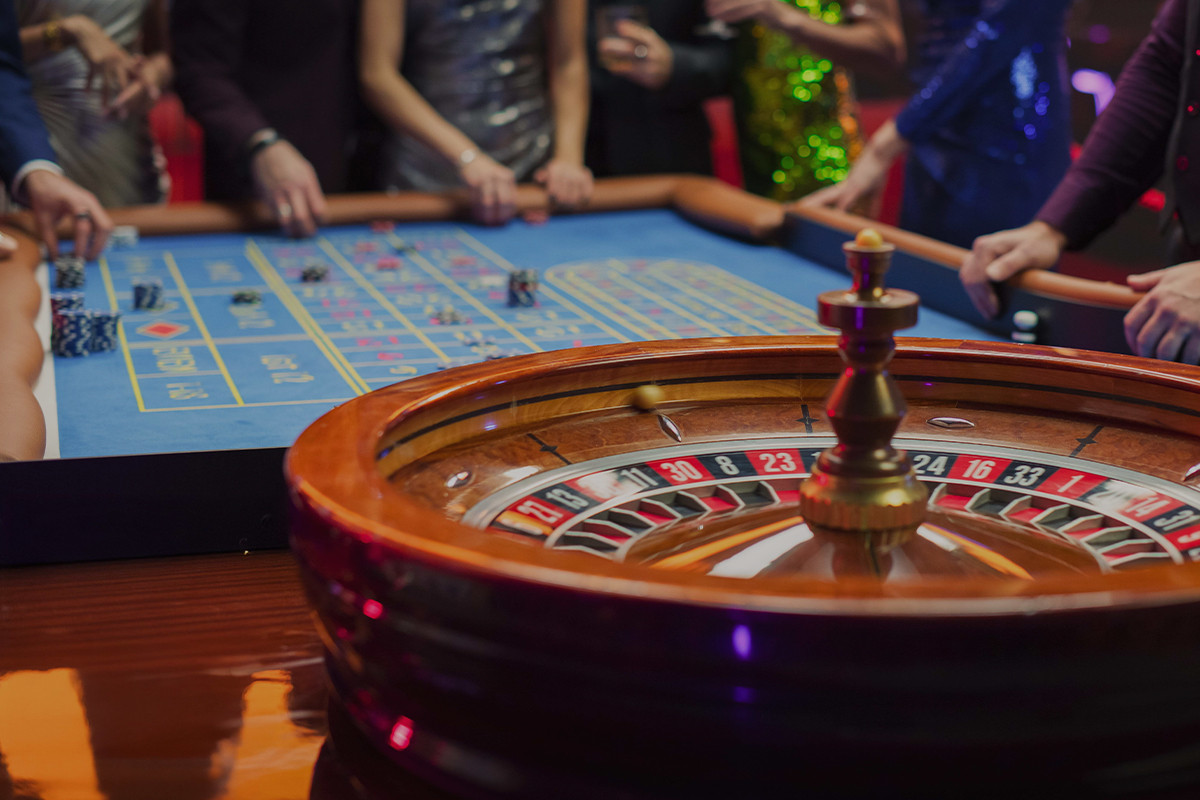 Roulettehjul och spelbord med spelare runt omkring.