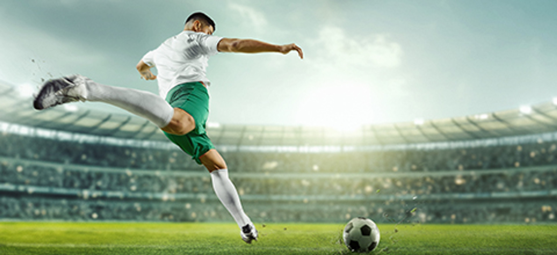 A soccer player taking a shot on goal in a packed stadium